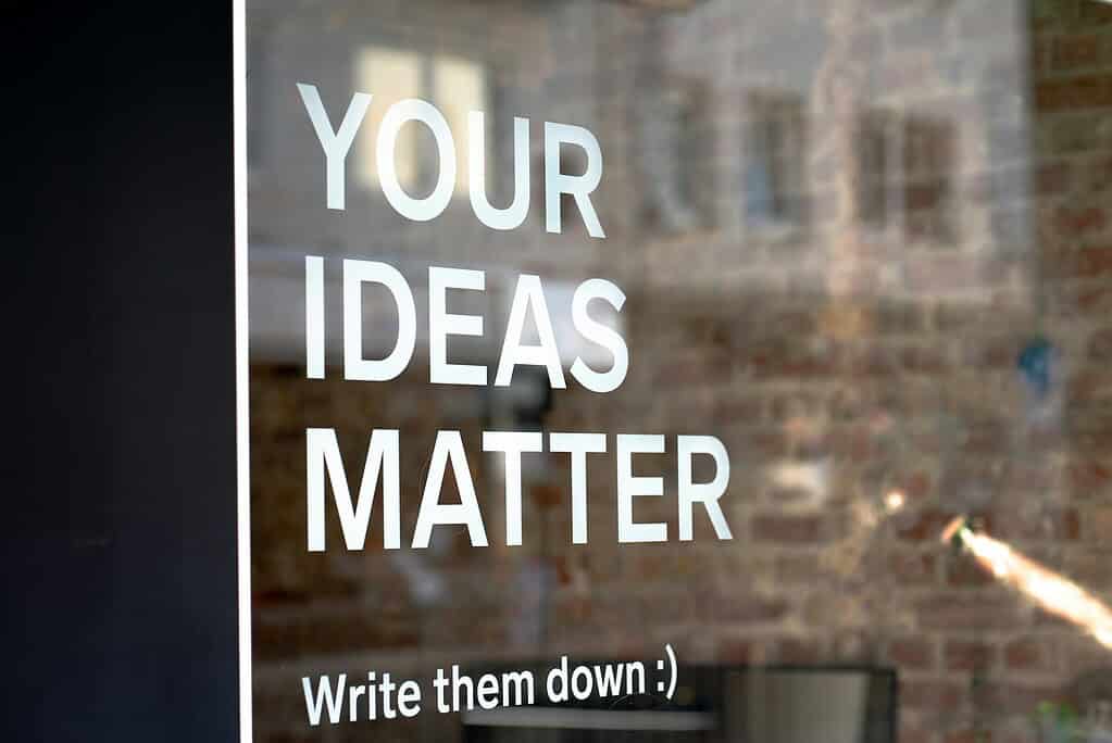 a glass window of an office with the words "Your Ideas Matter: Write them down."