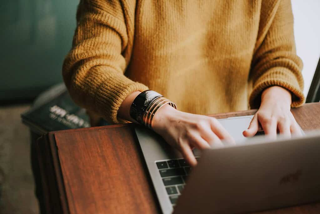 a writer typing on a laptop at their desk